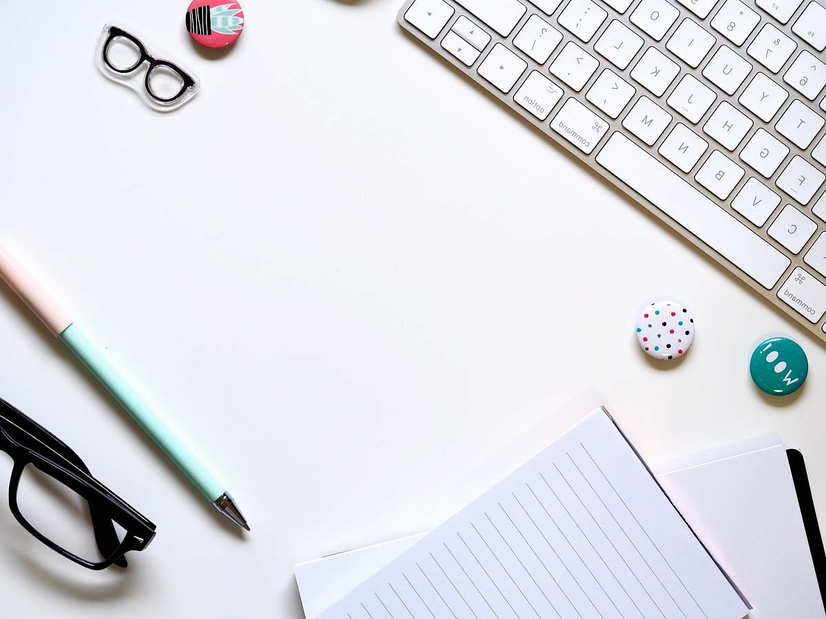 coffs harbour note paper, blue pen, and eyeglasses on white surface beside keyboard australia